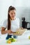 Young woman putting sliced green apple in bowl