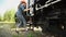 A young woman railroader get down the stairs and walking next to train.