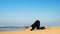 Young woman raises leg in yoga pose at endless blue ocean