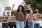 Young woman raising fist up, leading group of demonstrators