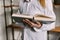 A young woman is reading a book in the background of a strong and modern bookcase. Close up