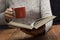 Young woman reading a book and holding cup of tea or coffee. Toned image