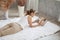 Young woman reading book while lying on White furry carpet in living room at home in quarantine