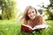 Young woman reading book at park lying down on grass