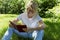 Young woman reading a book in a park on a sunny summer day. Blonde in a white T-shirt and jeans. Leisure and hobbies