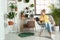 Young woman reading book in room with home plants