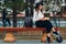 Young woman reading book and sitting on bench with electric scooter at the city