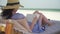 Young woman reading book on white beach by ocean.