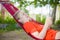 Young woman reading on electronic tablet reader relaxing in hammock under palm trees