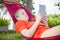 Young woman reading on electronic tablet reader relaxing in hammock under palm trees