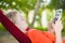 Young woman reading on electronic tablet reader relaxing in hammock under palm trees