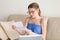 Young woman reading mail letter sitting with laptop on couch