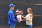 Young woman receiving beautiful flowers and gift from delivery man outdoors