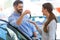 Young woman receiving keys from a car dealer