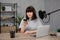 Young woman recording a podcast using smartphone, laptop, microphone and headphones