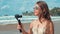 Young woman recording video outdoor. Joyful vlogger girl looking camera at beach