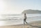 Young woman in red checkered shirt, jeans, white sneakers walking along beach and the stormy ocean on sunny winter day