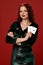 Young woman with a red curly hair holding aces, on a red background. Poker