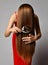 Young woman in red dress combing her long silky straight hair with vintage metal comb