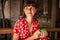 Young woman in red dress drinking a coffee in a tropical restaurant on Bali island. Travel, jungle, rainforest of Indonesia.