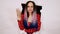 Young woman in red dress with fan in hole of white background in studio. Pretty lady waving fan, escaping from heat.