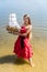 Young woman in red dress holding ship model on seashore