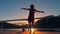 Young woman in a red dress on pier dancing against bridges view in sunset