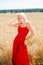Young woman in a red dress posing in a wheat field