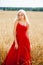 Young woman in a red dress posing in a wheat field