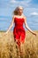 Young woman in a red dress posing in a wheat field