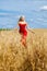 Young woman in a red dress posing in a wheat field