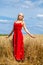 Young woman in a red dress posing in a wheat field