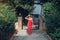 Young woman in red dress walks in summer exotic garden