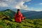 Young woman in red jacket sitting in yoga pose in mountains