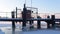 Young woman in red long jacket walks on snow-covered pier standing on bank of frozen river