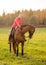 Young woman and red mare horse in autumn field