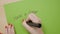 Young woman with red nail polish on her fingers writing have a good day message on a green paper using a black marker -