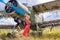 Young woman in a red pin up style dress stands by an abandoned green plane