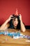 Young woman with red rubbed lipstick and cap, sitting tired at table in messy room after birthday party