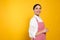 Young woman in red striped apron on yellow background, space for text