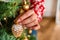 A young woman in a red sweater hangs Christmas toys on the tree at home