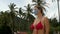 Young woman in red swimsuit on beach on sea coast on palm trees background