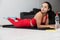 Young woman in red tracksuit doing exercise or yoga at home. Relaxed calm sporty girl lying on her stomach during