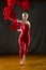 Young woman in red unitard swirling red fabric in studio.
