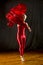 Young woman in red unitard swirling red fabric in studio.