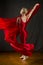 Young woman in red unitard swirling red fabric in studio.