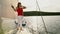 Young woman in red and white clothes standing on deck of sailing boat