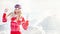 Young woman in red winter pullover, white hat and ski goggles smile happy, blurred snow country background, free space for text