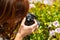 A young woman with reddish hair takes macro photographs of flowers with her camera in Caceres