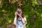 A young woman with reddish hair takes photographs with her camera next to a wall covered with bougainvillea Caceres